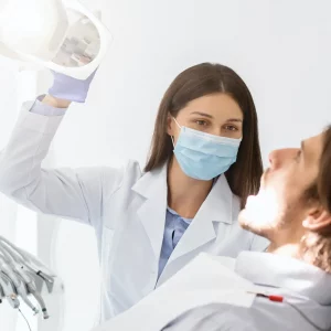 Dentist in mask turning on lamp before making check up
