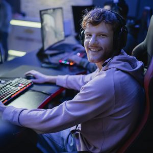 Smiling gamer looking at camera while playing video game in cyber club
