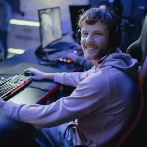 Smiling gamer looking at camera while playing video game in cyber club